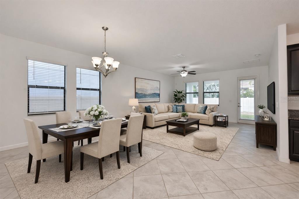 An open-concept living and dining area features tile flooring, neutral furniture, and a ceiling fan — 10616 GREAT CORMORANT DRIVE, RIVERVIEW, FL