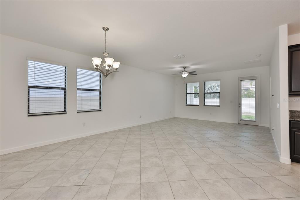 An open-concept dining and living area features white walls, tile flooring, and a ceiling fan — 10616 GREAT CORMORANT DRIVE, RIVERVIEW, FL