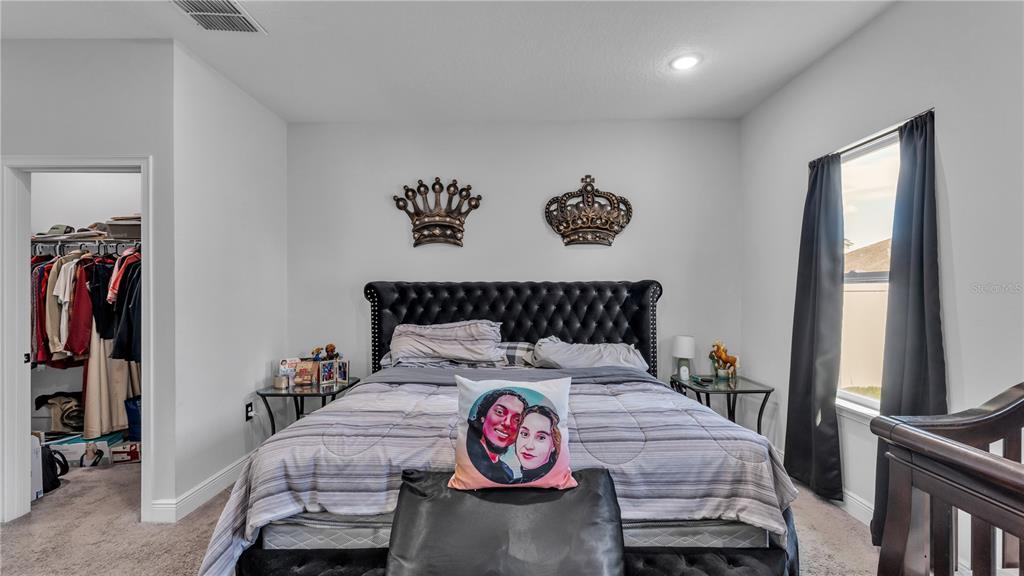 A bedroom features a tufted black headboard, two wall-mounted crowns, and a walk-in closet — 412 ARKANSAS COURT, KISSIMMEE, FL