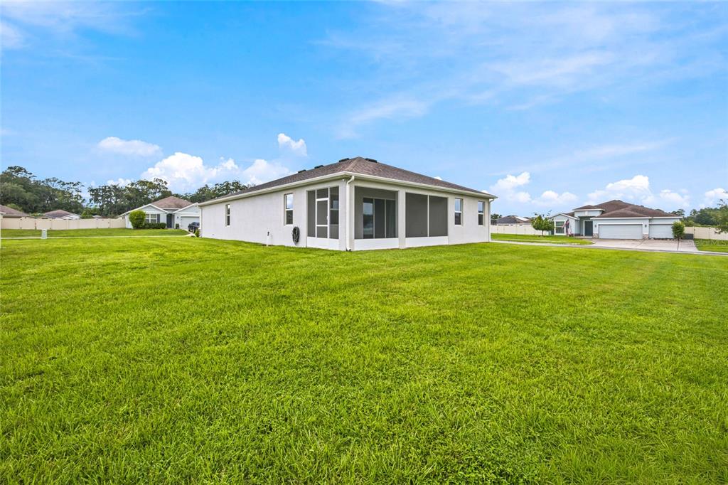 A rear exterior view of a single-story house with a screened-in lanai and large lawn — 1581 NE 50TH TERRACE, OCALA, FL