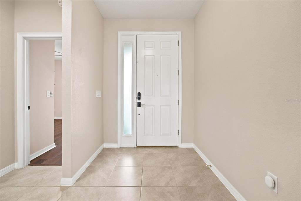 An entryway features a white front door with a sidelight, beige walls, and tiled flooring — 1581 NE 50TH TERRACE, OCALA, FL