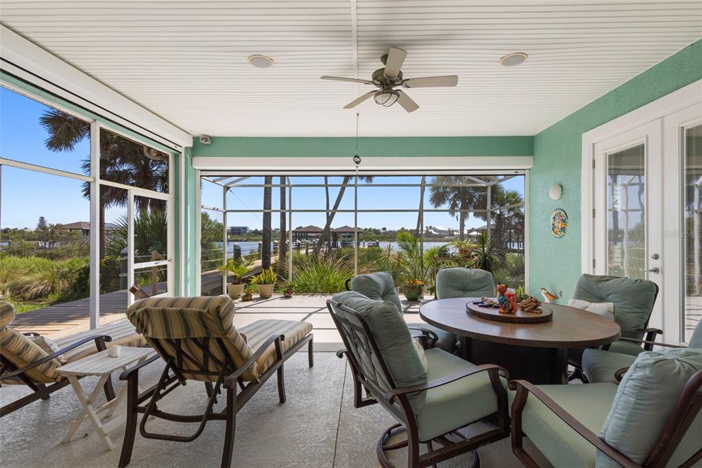 A screened-in patio features outdoor furniture, a ceiling fan, and a view of the water — 127 S RIVERWALK DRIVE, PALM COAST, FL