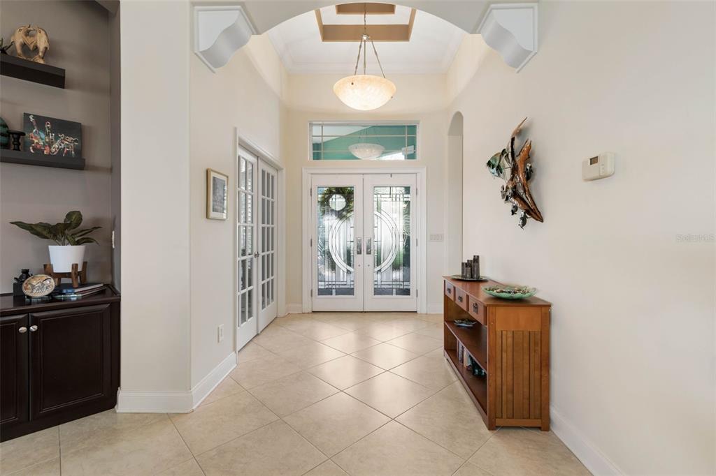 A bright entryway features tile flooring, a vaulted ceiling, double glass doors, and wooden furniture — 127 S RIVERWALK DRIVE, PALM COAST, FL
