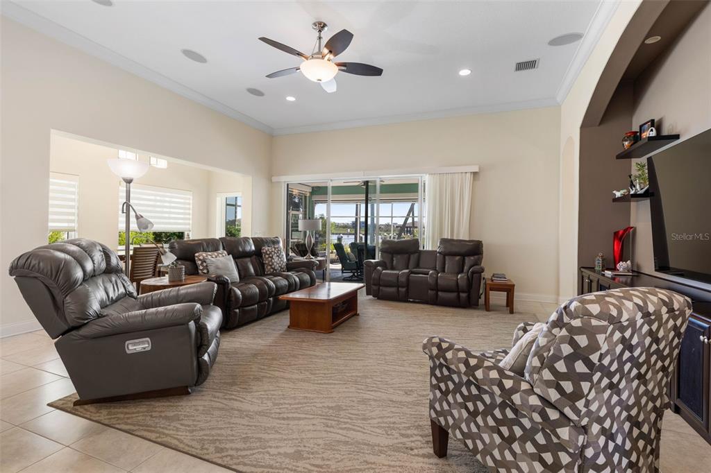 A living room with a ceiling fan, leather furniture, and sliding doors opening to a patio — 127 S RIVERWALK DRIVE, PALM COAST, FL
