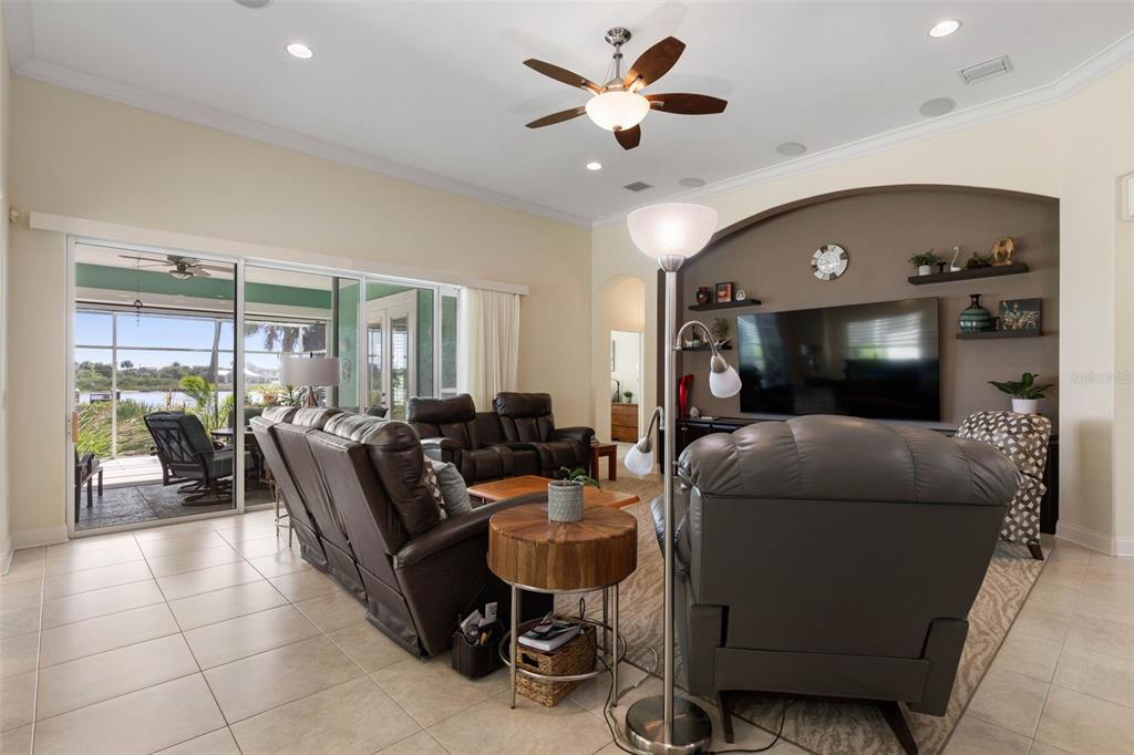 A living room features tile floors, leather furniture, a ceiling fan, and a large television — 127 S RIVERWALK DRIVE, PALM COAST, FL
