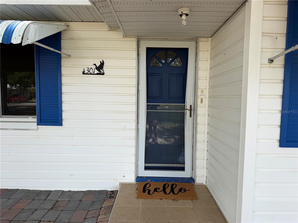 The exterior of a home features white siding, a blue front door, and a welcome mat — 301 S SEMINOLE AVENUE, MINNEOLA, FL