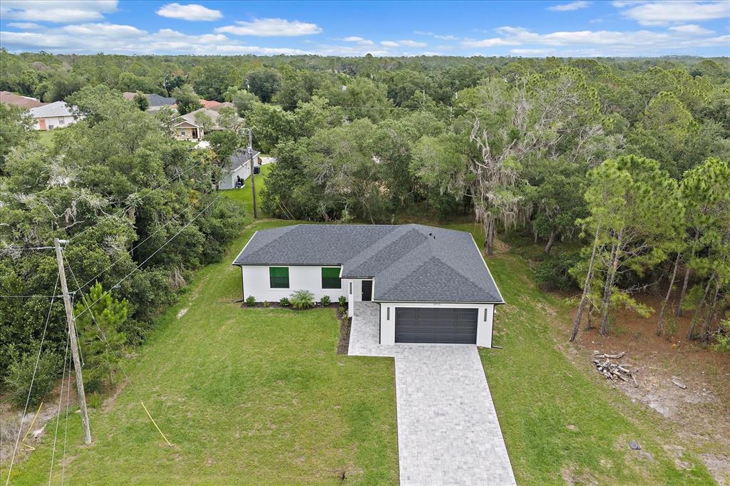 An aerial view shows a single-story house with a dark roof, garage, and paved driveway — 3938 ASCOT DRIVE, NORTH PORT, FL