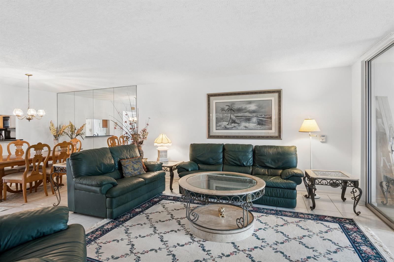 A living room features green leather sofas, a glass-topped coffee table, and a patterned area rug — 250 John F Kennedy Drive # 202, Atlantis FL 33462, ATLANTIS, FL