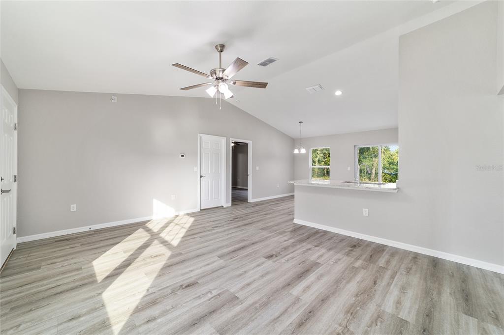 An open-concept living area features light gray walls, wood-look flooring, and a kitchen breakfast bar — 147 JUNIPER CIRCLE, OCALA, FL