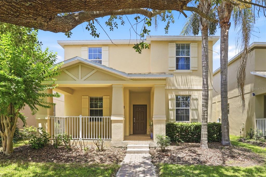 A two-story yellow stucco house with a front porch, white railings, and palm trees — 15621 SIGNATURE DRIVE, WINTER GARDEN, FL