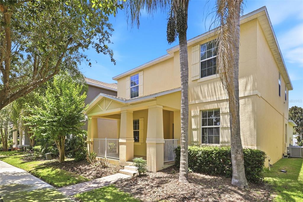 A two-story yellow house with a covered front porch and palm trees in the yard — 15621 SIGNATURE DRIVE, WINTER GARDEN, FL