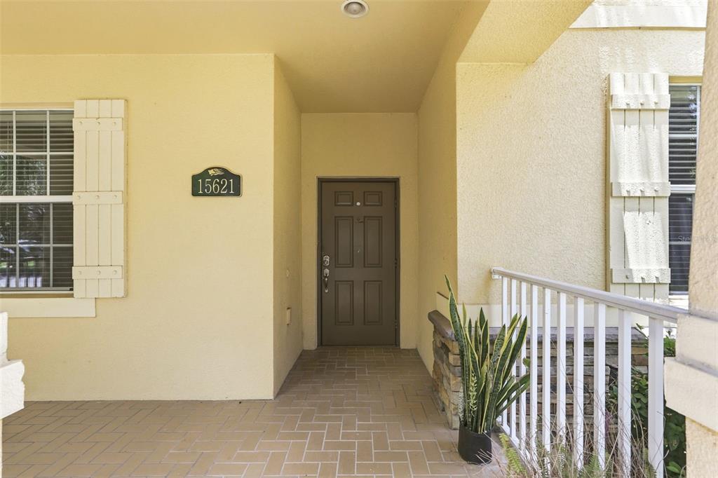 A covered entryway features a brown front door, a house number plaque, and stone accents — 15621 SIGNATURE DRIVE, WINTER GARDEN, FL