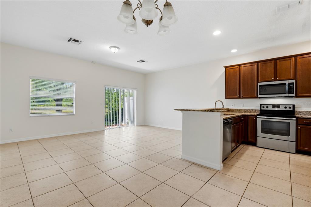 An open-concept kitchen and living area features tile flooring, dark wood cabinets, and stainless appliances — 1253 HONEY BLOSSOM DRIVE, ORLANDO, FL