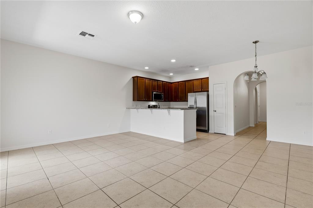 A kitchen with dark wood cabinets and stainless steel appliances overlooks a tiled living area — 1253 HONEY BLOSSOM DRIVE, ORLANDO, FL