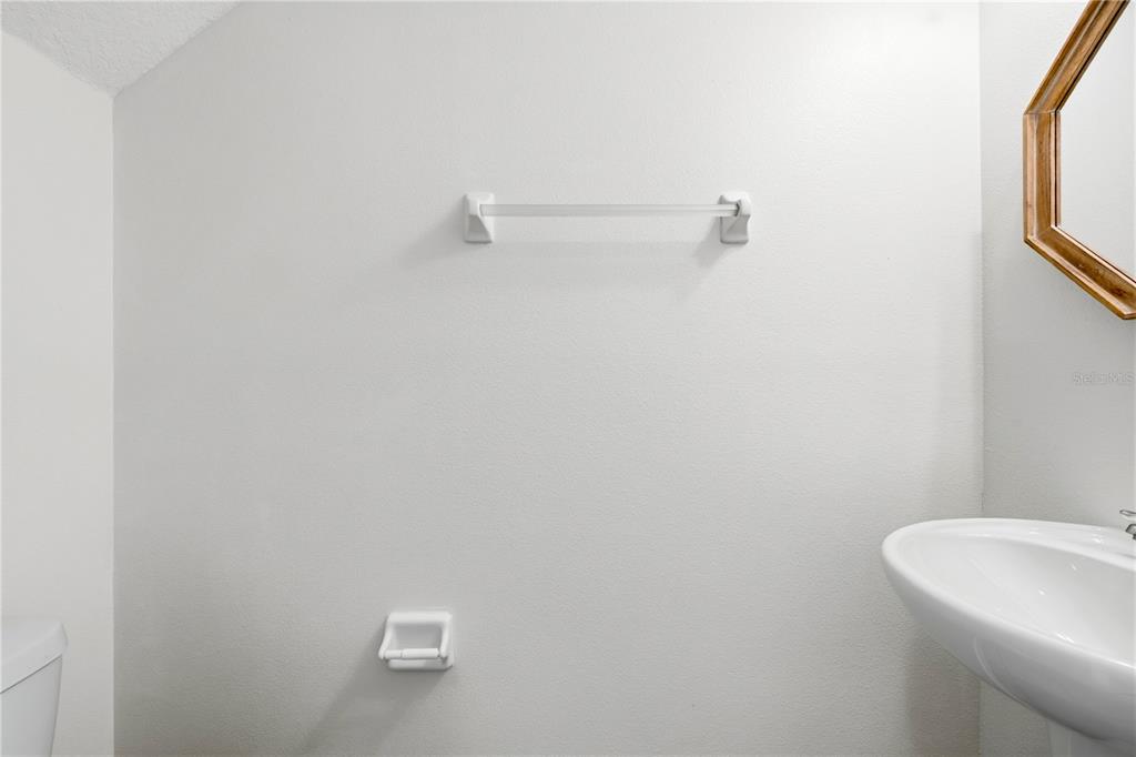 A bathroom features a white pedestal sink, a towel bar, and a toilet paper holder — 1253 HONEY BLOSSOM DRIVE, ORLANDO, FL