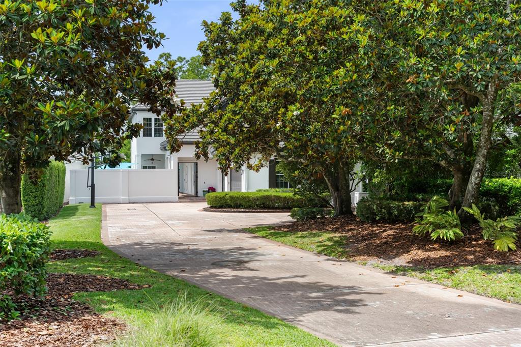 A long concrete driveway leads to a white two-story house surrounded by large trees — 9720 COVENT GARDEN DRIVE, ORLANDO, FL