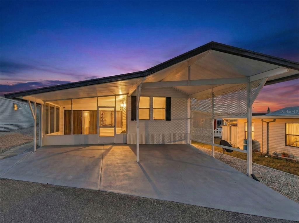 A mobile home exterior featuring a concrete carport and an attached screened-in porch at dusk — 251 PATTERSON ROAD UNIT C29, HAINES CITY, FL