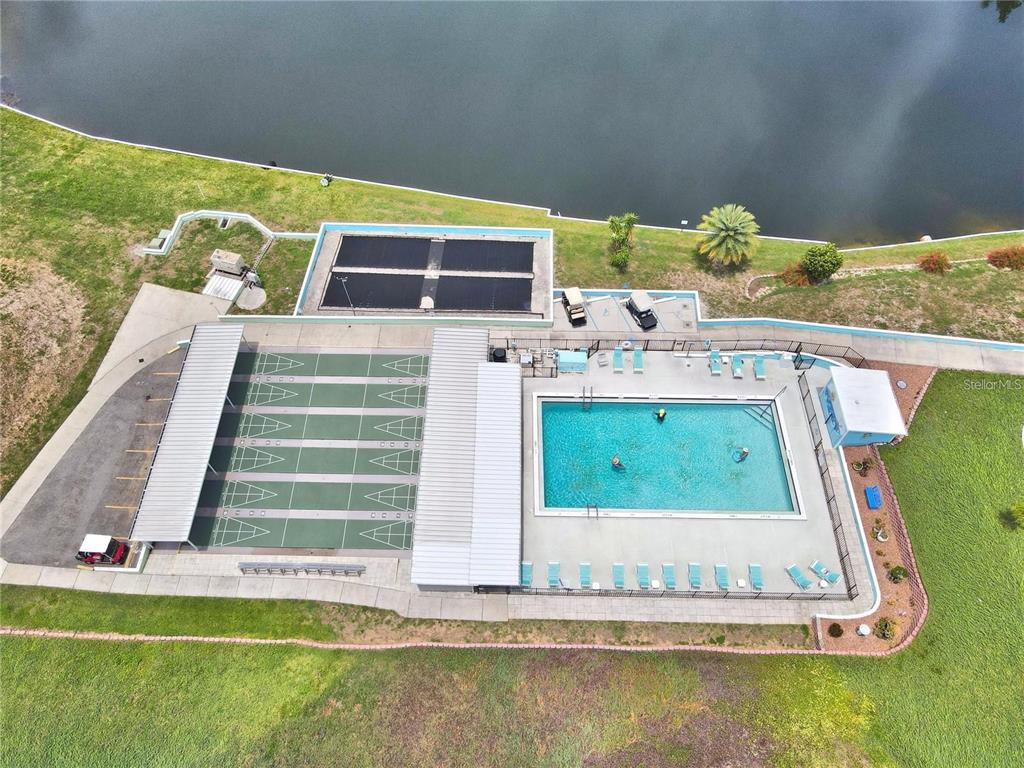 An aerial view shows a swimming pool, shuffleboard courts, and a lake — 251 PATTERSON ROAD UNIT C29, HAINES CITY, FL