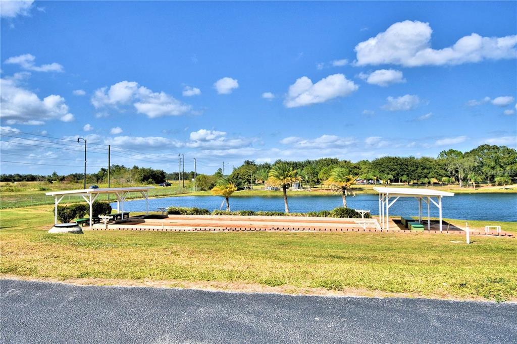 A bocce ball court sits between two covered pavilions next to a small lake — 251 PATTERSON ROAD UNIT C29, HAINES CITY, FL