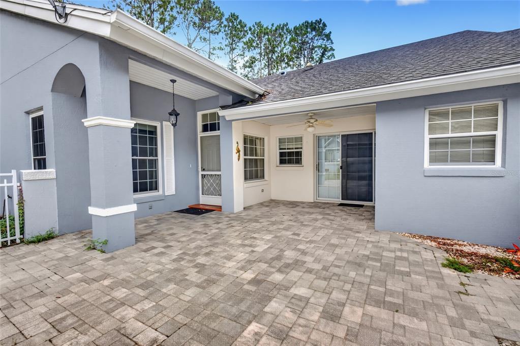 A paved patio area sits between two sections of a light blue house with windows — 8055 SW 115TH LOOP, OCALA, FL