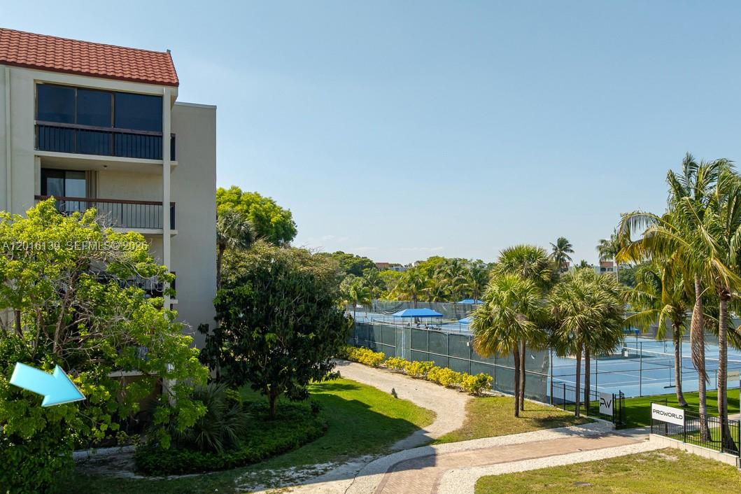 An exterior view shows a multi-story apartment building next to a fenced tennis court — 825 Egret Cir # 110, Delray Beach FL 33444, DELRAY BEACH, FL