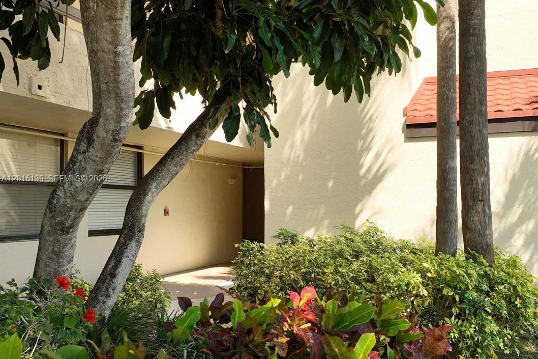 A view of a building exterior with a walkway, trees, and landscaping — 825 Egret Cir # 110, Delray Beach FL 33444, DELRAY BEACH, FL