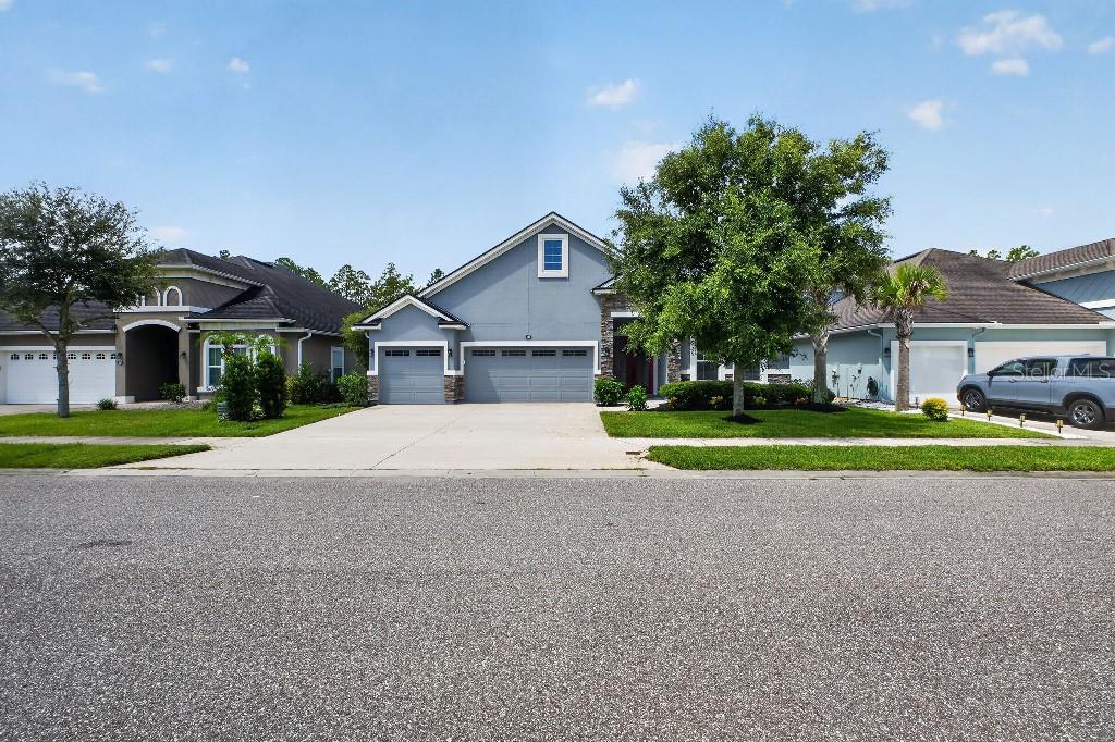 A single-story house with a gray exterior, a three-car garage, and a large front tree — 161 S COOPERS HAWK WAY, PALM COAST, FL