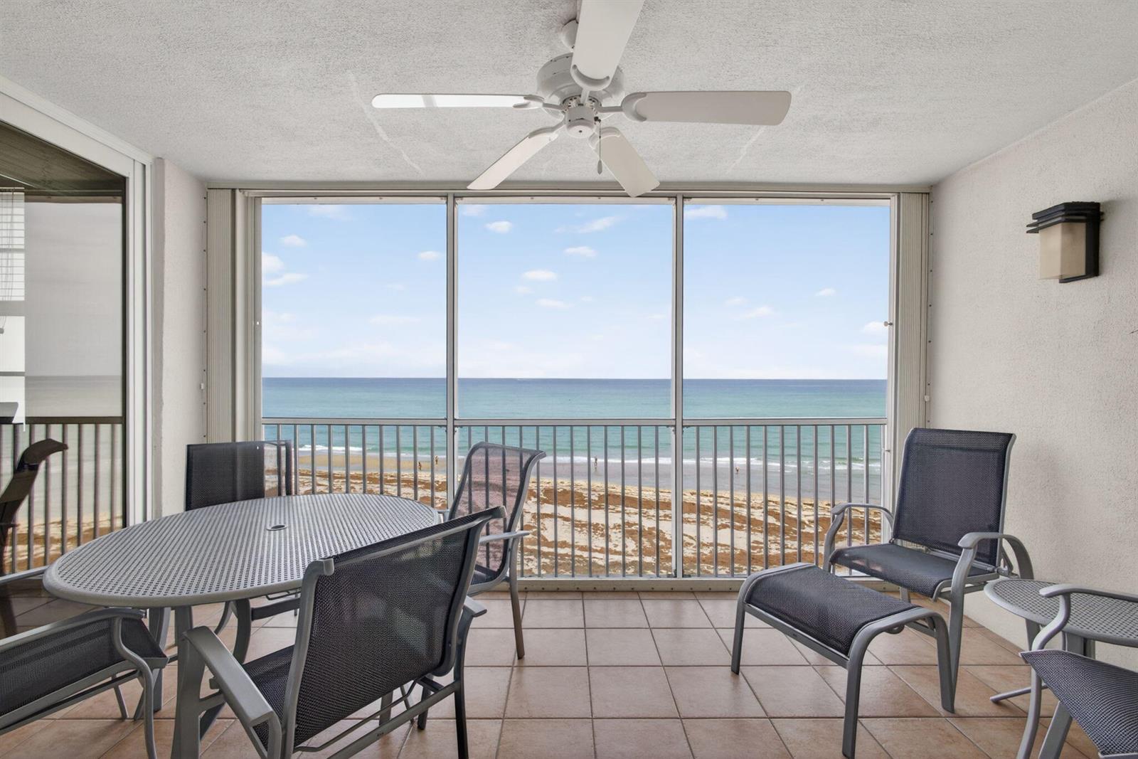A screened-in balcony with tile flooring, patio furniture, and a direct ocean view — 840 Ocean Drive # 406, Juno Beach FL 33408, JUNO BEACH, FL