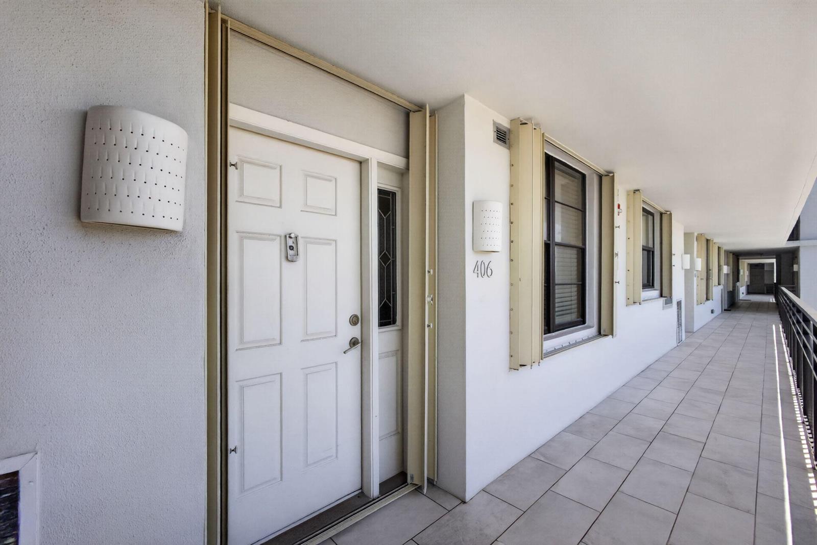 An exterior hallway features white doors, unit number 406, and tiled flooring — 840 Ocean Drive # 406, Juno Beach FL 33408, JUNO BEACH, FL