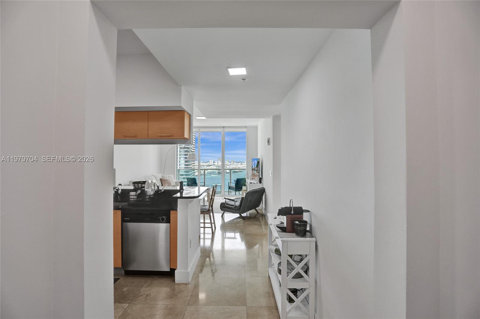 A kitchen with stainless steel appliances and light wood cabinets overlooks a living area — 31 SE 5th St # 4112, Miami FL 33131, MIAMI, FL
