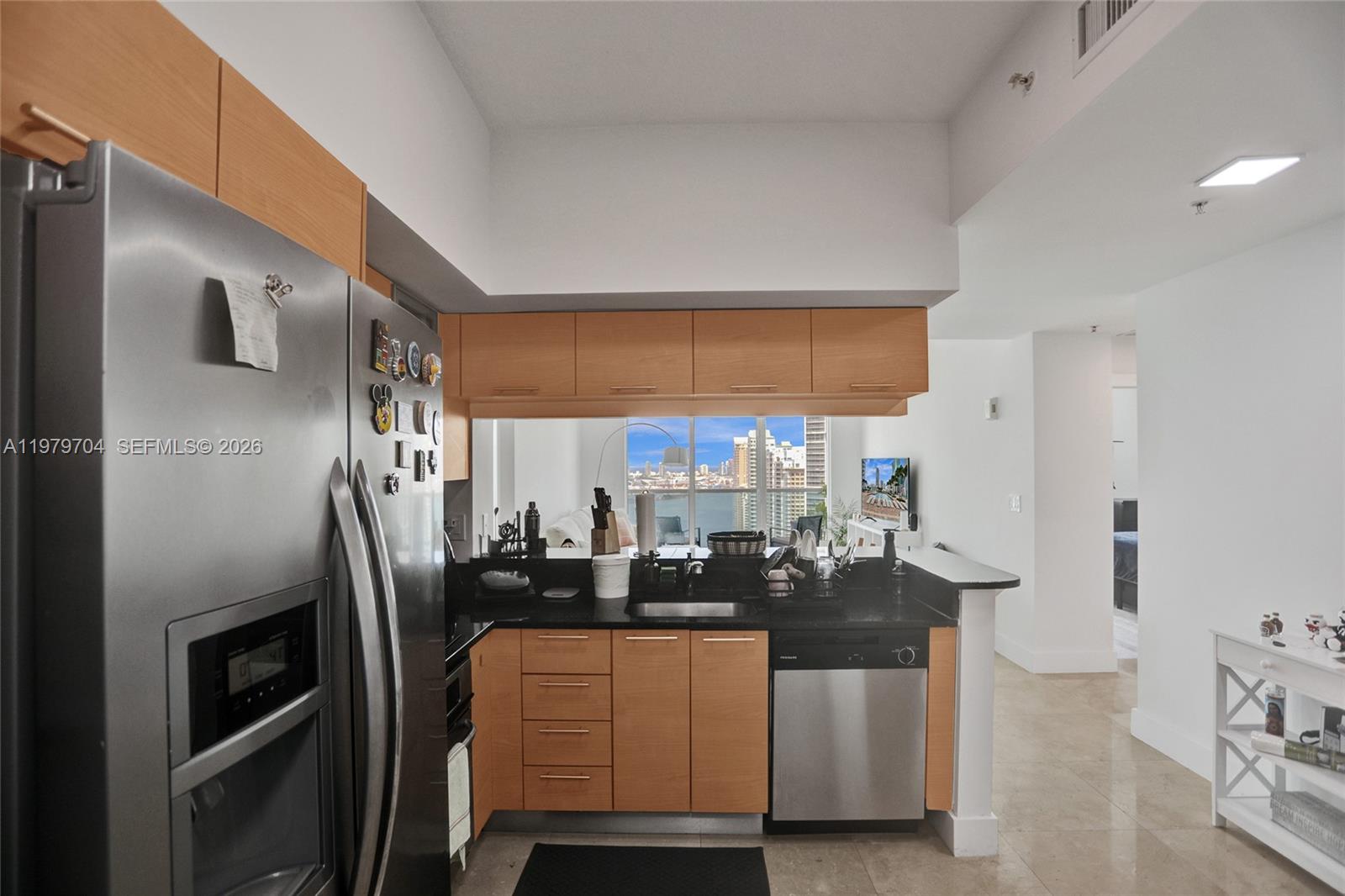 A kitchen features light wood cabinets, black countertops, stainless steel appliances, and a city view — 31 SE 5th St # 4112, Miami FL 33131, MIAMI, FL
