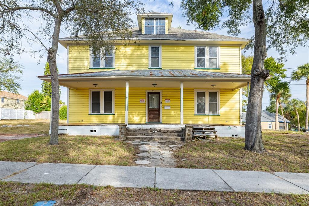 A two-story yellow house with a front porch and a stone walkway — 553 DIVISION STREET, TARPON SPRINGS, FL