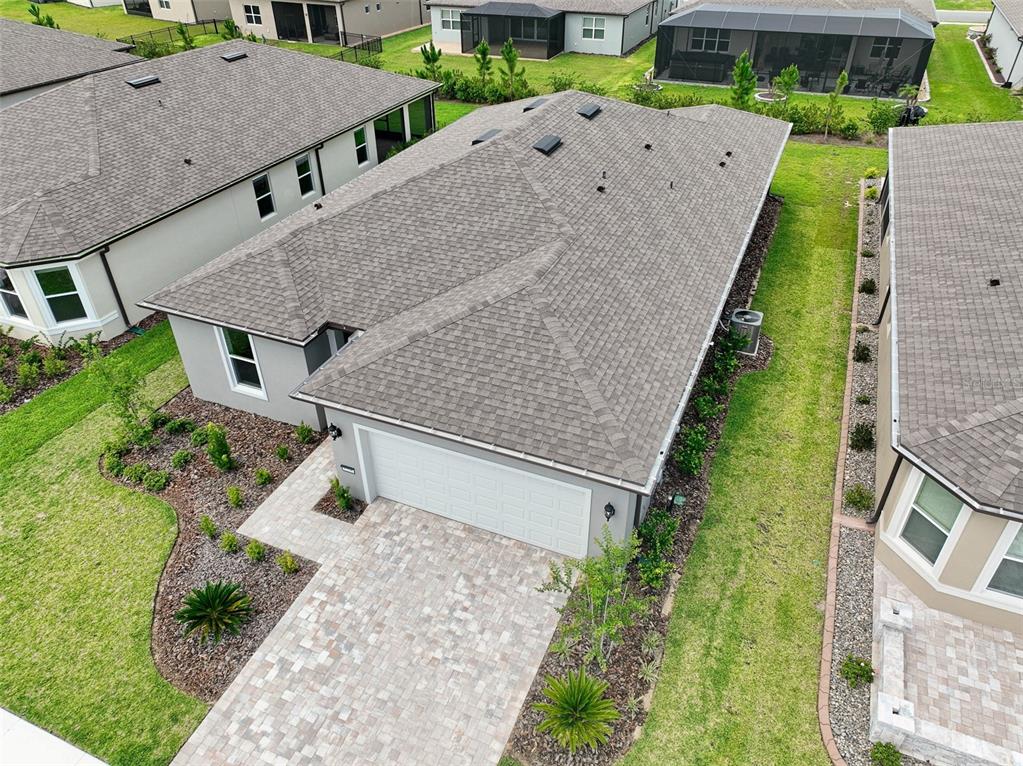 An aerial view shows a suburban house with a gray shingled roof and paver driveway — 8348 SW 58TH LOOP, OCALA, FL