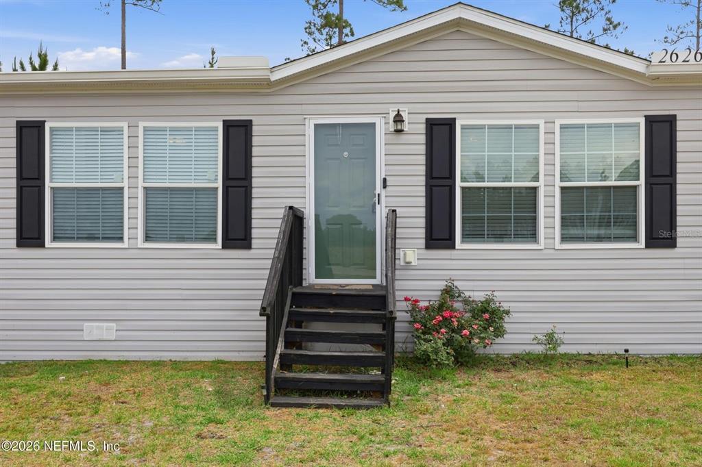 The exterior of a light gray house features a central front door and black shutters — 2626 WILL ELLEDGE ROAD, GLEN ST MARY, FL