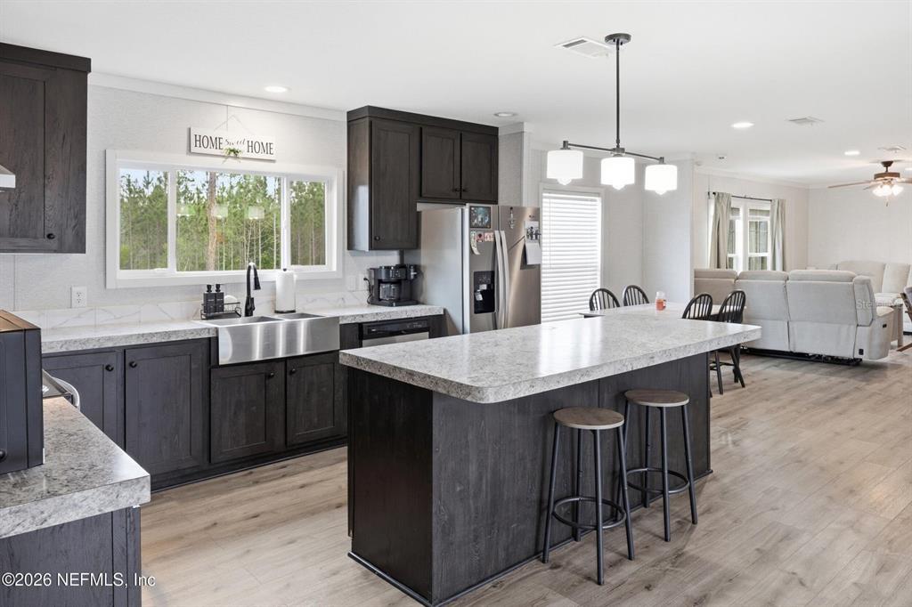 A kitchen features dark wood cabinets, a large island with bar stools, and stainless appliances — 2626 WILL ELLEDGE ROAD, GLEN ST MARY, FL