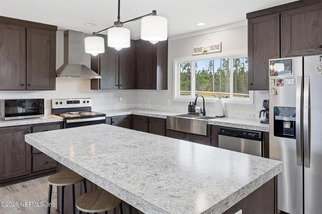 A kitchen features dark wood cabinets, a large quartz island, and stainless steel appliances — 2626 WILL ELLEDGE ROAD, GLEN ST MARY, FL