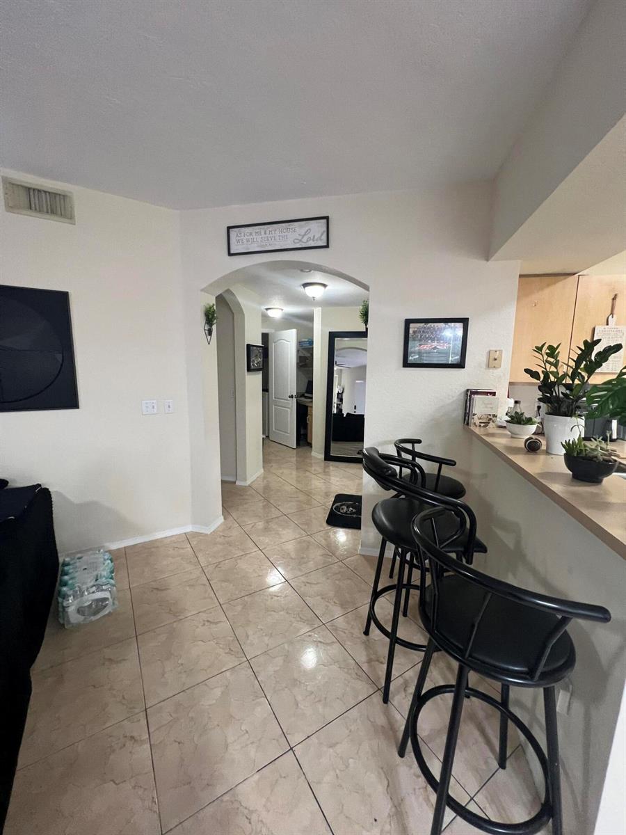 A tiled kitchen area features a breakfast bar with black stools and an arched entryway — 607 Belmont Place, Boynton Beach FL 33436, BOYNTON BEACH, FL