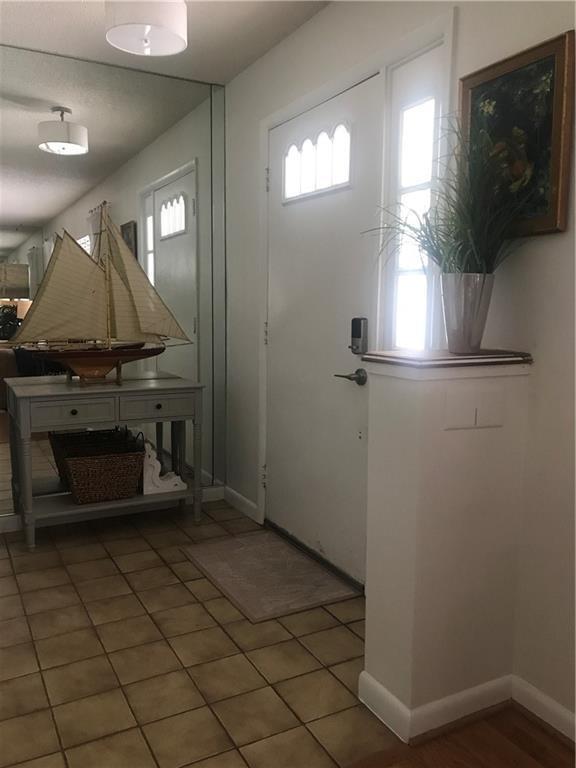 An entryway features a tiled floor, a mirrored wall, a console table, and a front door — 2536 44th Avenue, Vero Beach FL 32966, VERO BEACH, FL