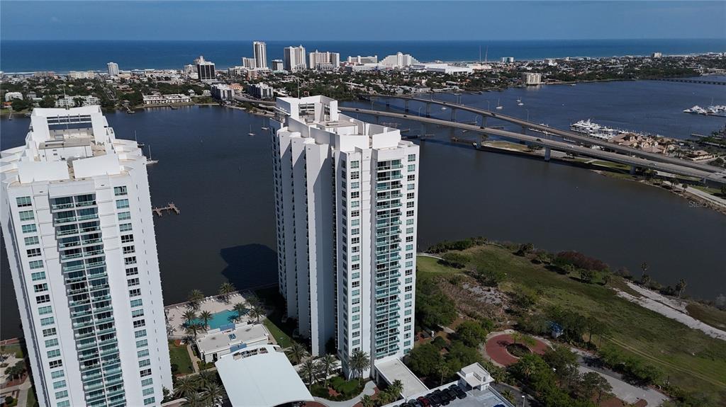 An aerial view shows two tall white residential towers situated near a bay and bridge — 231 RIVERSIDE DRIVE UNIT 1110, DAYTONA BEACH, FL
