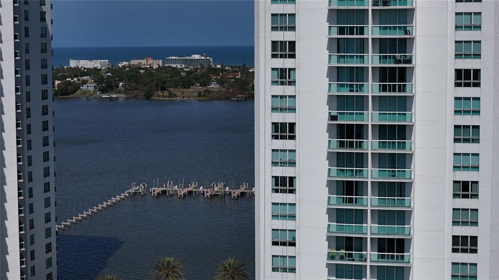 An exterior view shows two tall white apartment buildings overlooking a bay and a pier — 231 RIVERSIDE DRIVE UNIT 1110, DAYTONA BEACH, FL