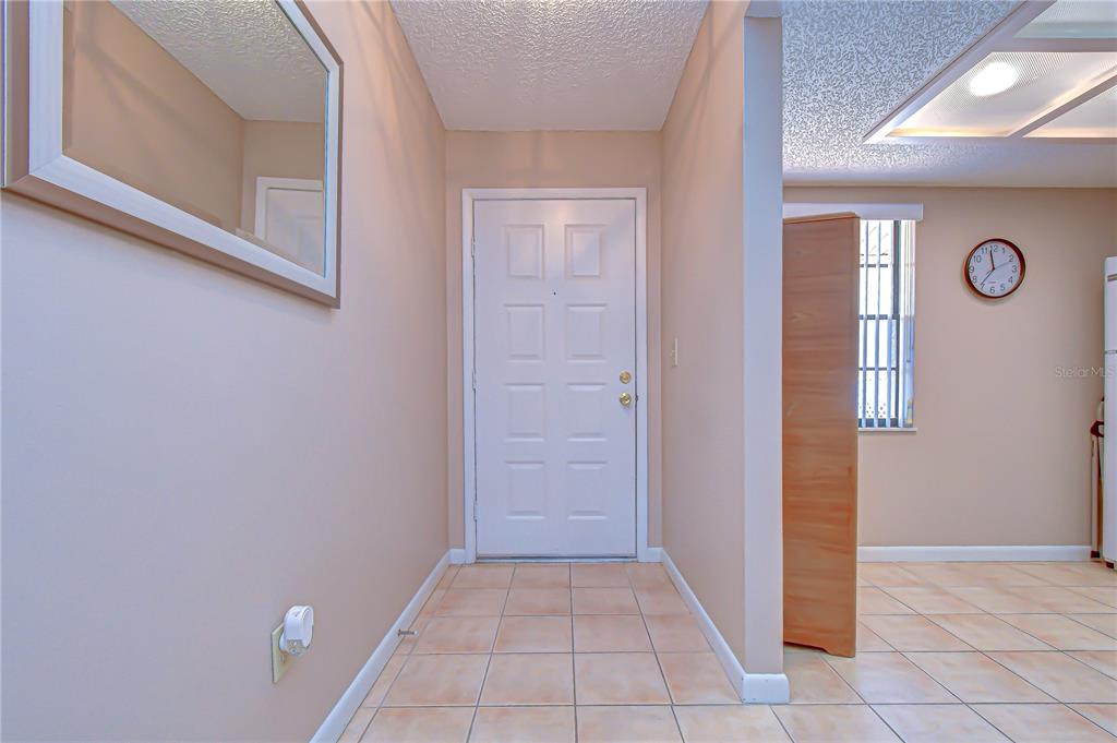 An entryway features a white front door, beige walls, and light-colored floor tiles — 38235 BOXWOOD DRIVE UNIT 38235, ZEPHYRHILLS, FL