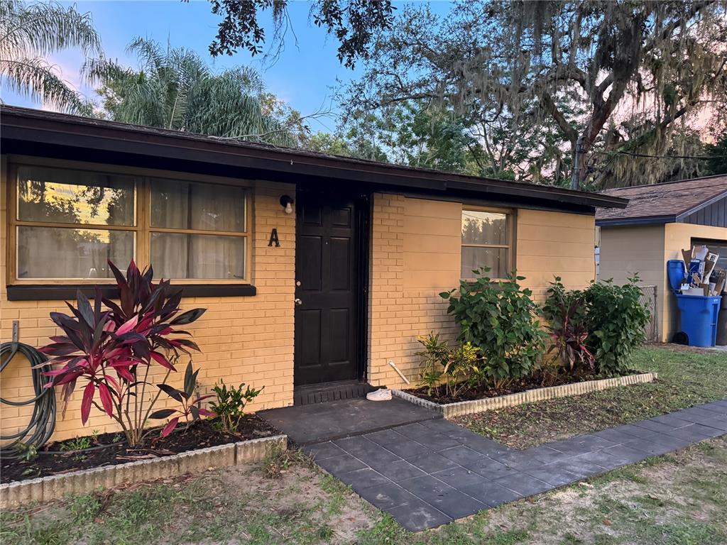 A single-story tan brick house with a black door, dark trim, and a tiled walkway — 1801 N TAYLOR ROAD, BRANDON, FL