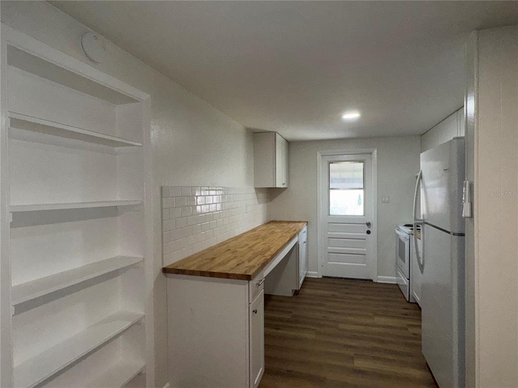 A kitchen features white cabinets, a wood countertop, a subway tile backsplash, and open shelving — 1801 N TAYLOR ROAD, BRANDON, FL