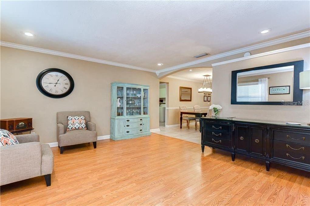 A living room with light wood floors, a blue hutch, and a black sideboard — 5121 ELLENDALE AVENUE, TAMPA, FL