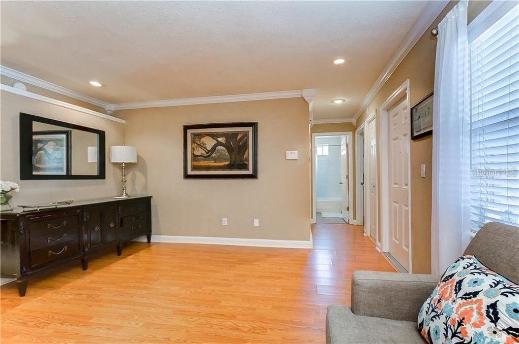A living room with light wood flooring, a dark sideboard, and a framed landscape painting — 5121 ELLENDALE AVENUE, TAMPA, FL