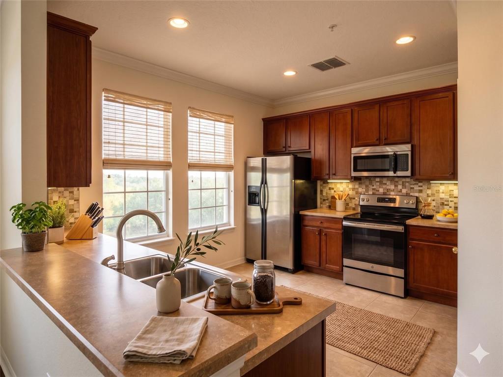 A kitchen features wood cabinets, stainless steel appliances, and a double sink on the island — 10230 LAKE DISTRICT LANE UNIT 37B, ORLANDO, FL
