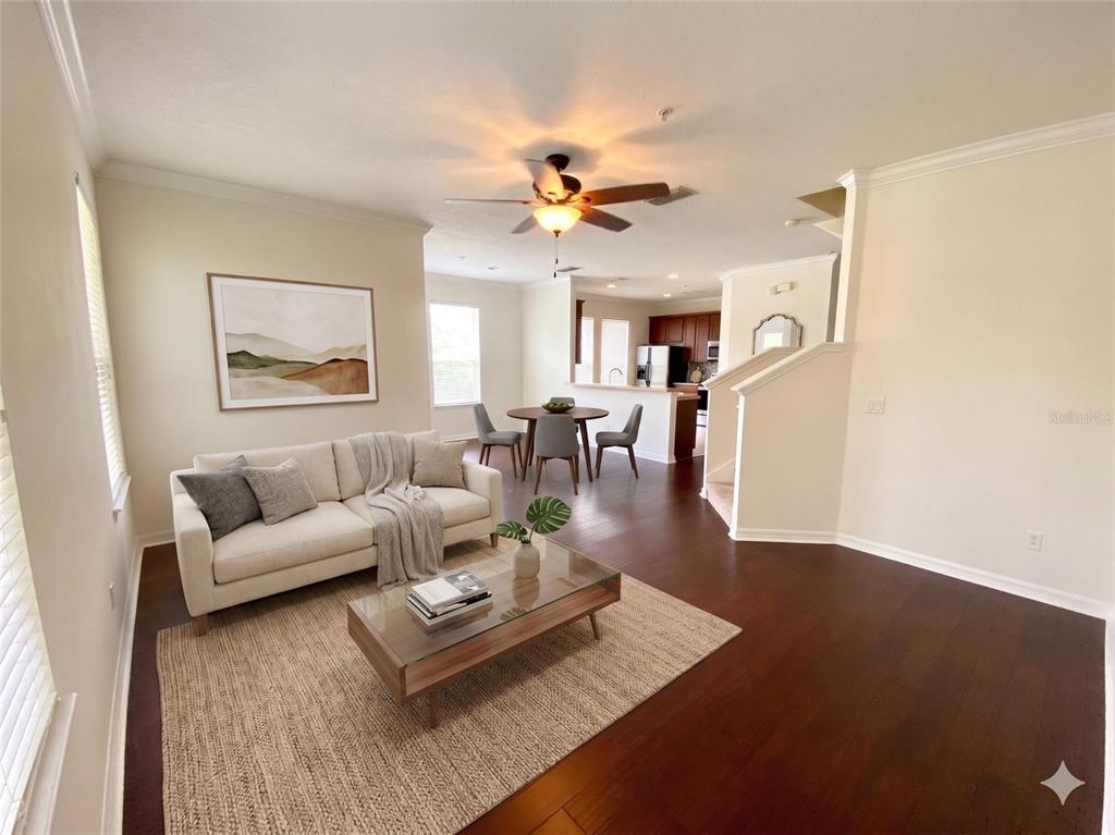 An open-concept living and dining area features hardwood floors, a ceiling fan, and neutral walls — 10230 LAKE DISTRICT LANE UNIT 37B, ORLANDO, FL