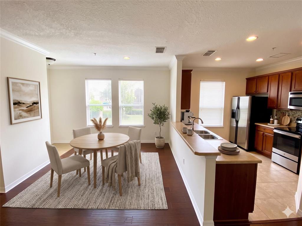 A dining area with a round table and chairs sits adjacent to a kitchen — 10230 LAKE DISTRICT LANE UNIT 37B, ORLANDO, FL