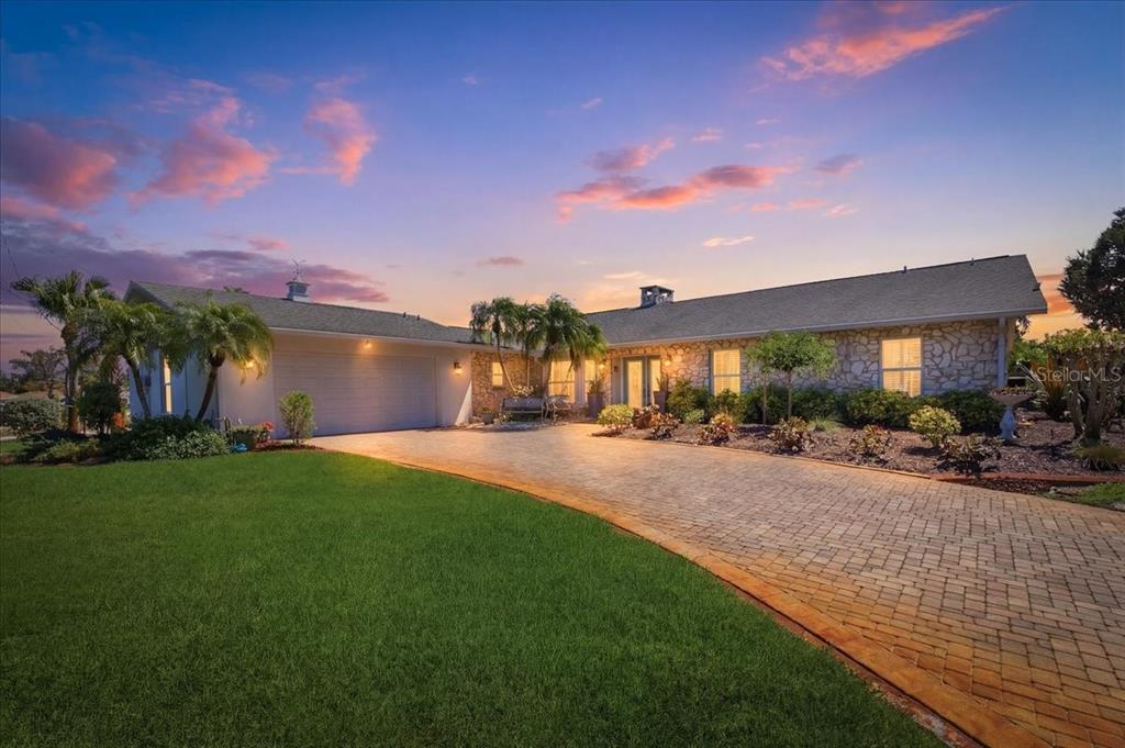 A single-story house with a stone facade and a curved brick driveway at sunset — 1231 BAYSHORE DRIVE, ENGLEWOOD, FL