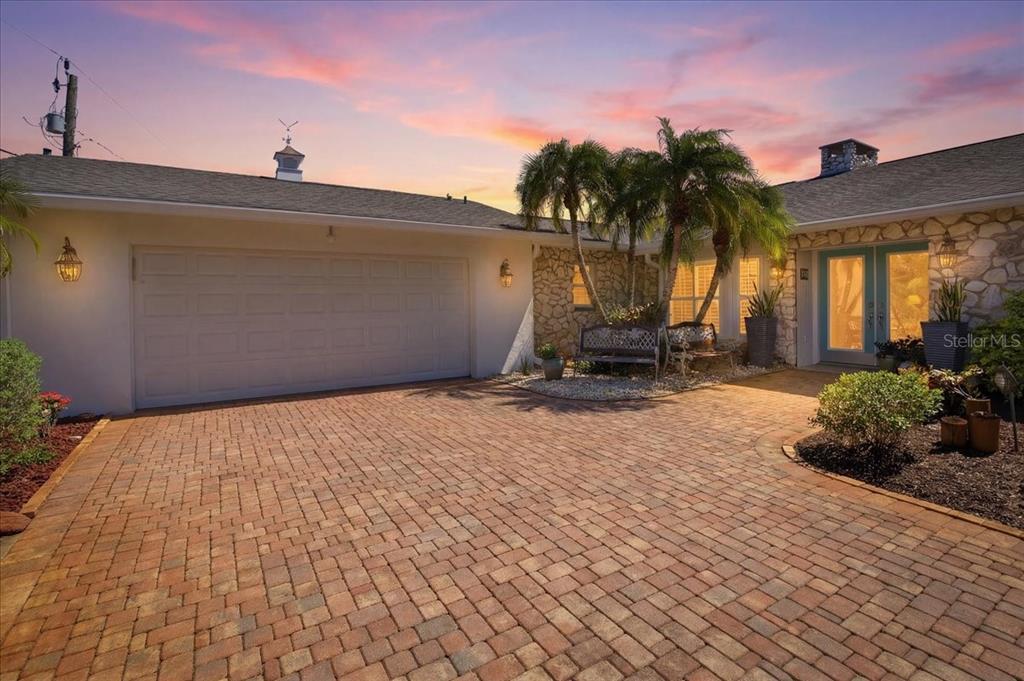 A single-story house with a stone facade and a brick driveway at sunset — 1231 BAYSHORE DRIVE, ENGLEWOOD, FL